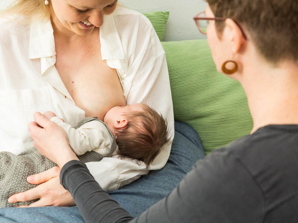 Stillende Mutter mit Hebamme Stillende Mutter mit Hebamme